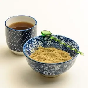 Essiac Tee in einer Tasse und gemahlene Kräuter in einer Schale