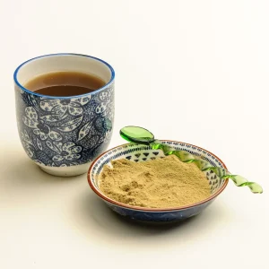 Eine Tasse Essiac-Tee und eine Schale mit Essiac-Kräuterpulver.